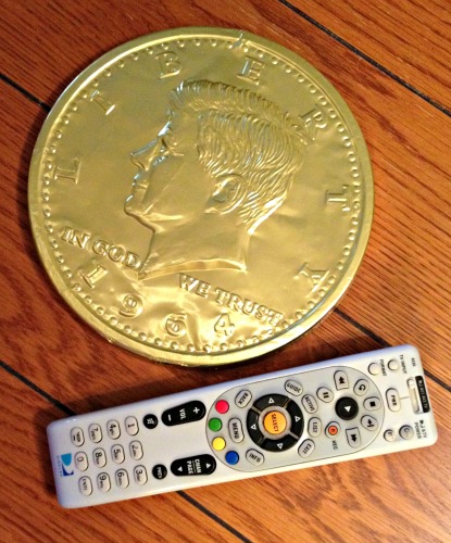 The Mega Gold Coin next to a normal sized remote control.